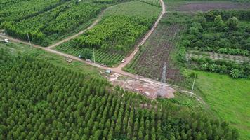 vista aérea de escavadeiras estão trabalhando nas fundações de postes de alta tensão e nas pernas de postes de alta tensão. vista superior da construção de linhas de energia na floresta. video