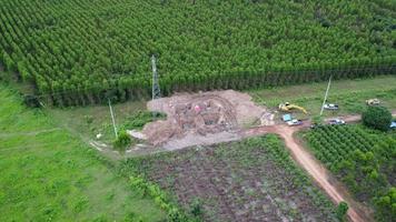 vista aérea de las excavadoras están trabajando en los cimientos de las torres de alta tensión y las patas de los postes de alta tensión. vista superior de la construcción de líneas eléctricas en el bosque. video