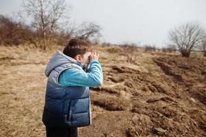 Boy look through hands binoculars. photo