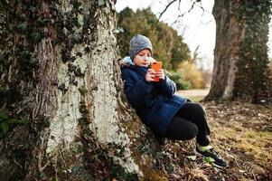 niño mirando el teléfono móvil en el parque valtice, contra un gran árbol. foto