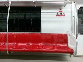 Red row of seats on the train and signs warning No eating or drinking, No Flammable goods, No animals and No smoking in Thai and English. photo