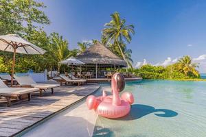 Summer tourism swimming pool inflatable pink flamingo, luxury resort hotel poolside. Happy cloudy sky, tropical paradise island infinity pool sea view. Vacation, holiday fun landscape. Relax leisure
