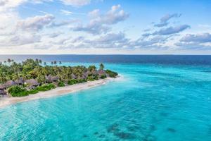 vista aérea de pájaros de la hermosa playa tropical paraíso maldivas en la isla. concepto de vacaciones de viajes de verano. increíble costa de la isla, laguna oceánica, cielo nublado, idílico paisaje exótico. paisaje natural foto