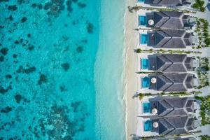 vista aérea superior de villas con piscina, bungalows en la playa tropical paraíso de maldivas. increíble laguna de mar azul turquesa, agua de la bahía del océano. destino de vacaciones de viaje de lujo. hermoso paisaje aéreo soleado foto