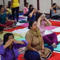 New Delhi, India, June 19 2022 -Group Yoga exercise session for people of different age groups in Balaji Temple, Vivek Vihar, International Yoga Day, Big group of adults attending yoga class in temple photo