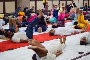 New Delhi, India, June 19 2022 -Group Yoga exercise session for people of different age groups in Balaji Temple, Vivek Vihar, International Yoga Day, Big group of adults attending yoga class in temple photo