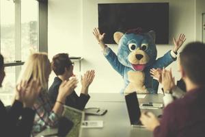 boss dresed as bear having fun with business people in trendy office photo