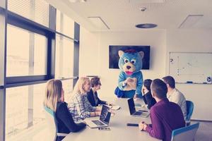 boss dresed as bear having fun with business people in trendy office photo