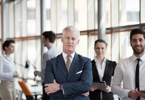 retrato de un hombre de negocios senior como líder con un grupo de personas en segundo plano como equipo foto