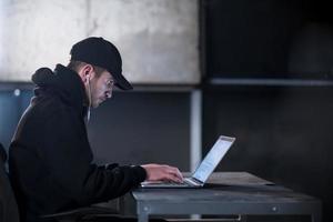 talented hacker using laptop computer while working in dark office photo