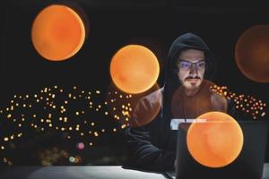 hacker using laptop computer while working in dark office photo
