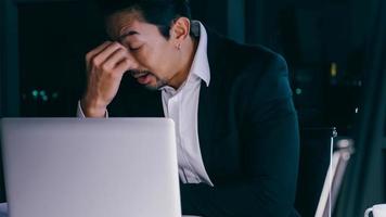 Stressed young Asian businessman working overtime at the office. photo