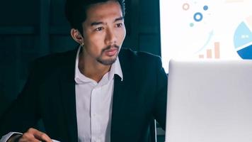 A young businessman concentrating on an analysis of work projects in his office until late at night. photo