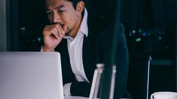 Stressed young Asian businessman working overtime at the office. photo