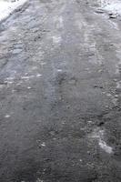 Damaged asphalt road with potholes caused by freezing and thawing cycles during the winter. Poor road photo