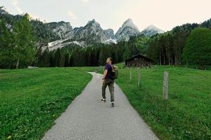 Back of man with backpack walking in mountains at Vorderer Gosausee, Gosau, Upper Austria. photo