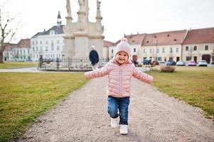 Baby girl with lollipop, wear pink jacket walking at Valtice town, Czech Republic. photo