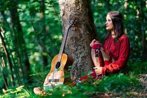 chica hippie con la guitarra en el bosque foto
