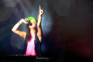 glamorosa chica DJ en el trabajo cantando en su consola en una fiesta foto