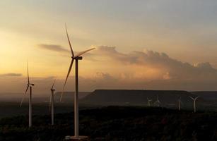 Wind energy. Wind power. Sustainable, renewable energy. Wind turbines generate electricity. Windmill farm on mountain with sunset sky. Green technology. Renewable resource. Sustainable development. photo