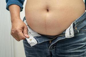 Overweight Asian woman show fat belly at office. photo