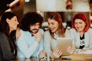 A group of friends hanging out in a cafe, and among them is a tablet. photo