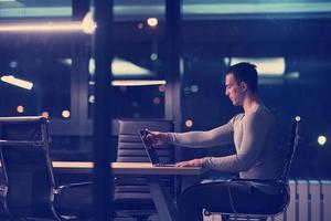 man working on laptop in dark office photo