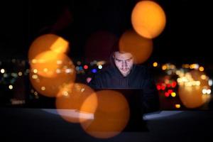 hacker using laptop computer while working in dark office photo