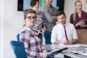 portrait of young business woman at office with team on meeting in background photo