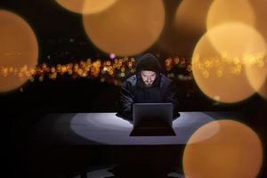 hacker using laptop computer while working in dark office photo