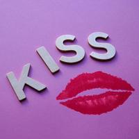labios y palabra de beso con letras de madera en el fondo rosa foto