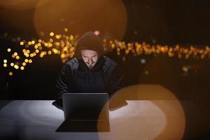 hacker using laptop computer while working in dark office photo