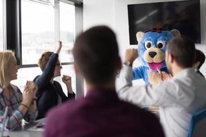 jefe vestido como oso divirtiéndose con gente de negocios en una oficina de moda foto