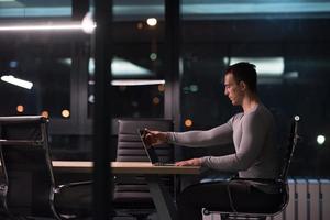 man working on laptop in dark office photo
