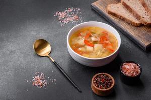 Closeup of a bowl of chicken noodle and vegetable soup on a concrete table photo