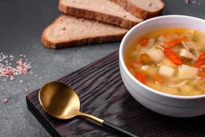 Closeup of a bowl of chicken noodle and vegetable soup on a concrete table photo