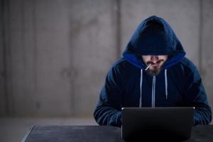 young hacker using laptop computer while working in dark office photo