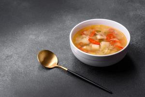 Closeup of a bowl of chicken noodle and vegetable soup on a concrete table photo