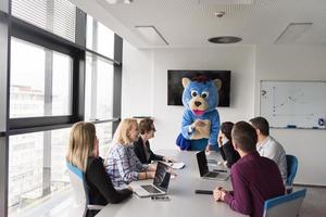 boss dresed as bear having fun with business people in trendy office photo