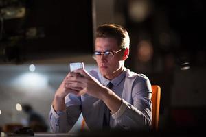 man using mobile phone in dark office photo