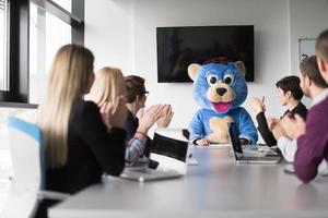 jefe vestido como oso divirtiéndose con gente de negocios en una oficina de moda foto