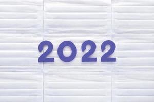 Violet felt new year numbers 2022 on white medical masks background. Inspired by trendy very peri color of the year 2022. Place for your text here. photo