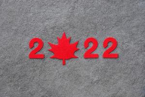 Red felt new year numbers 2022 on dark gray stone surface. Zero in the shape of a red maple leaf as a symbol of Canada. Review of the year. photo