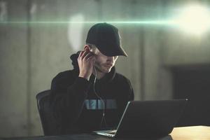 young talented hacker using laptop computer while working in dark office photo