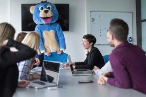 boss dresed as bear having fun with business people in trendy office photo