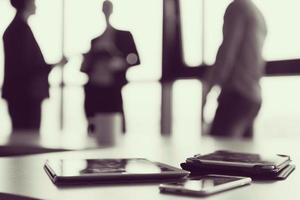 close up of tablet, business people on meeting in background photo