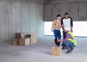 worker using laptop computer while showing house design plans photo
