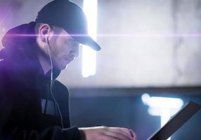 young talented hacker using laptop computer while working in dark office photo