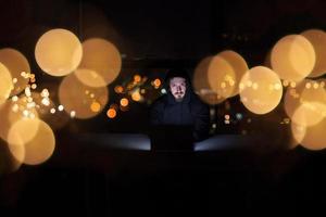 hacker using laptop computer while working in dark office photo
