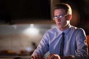 man working on computer in dark office photo